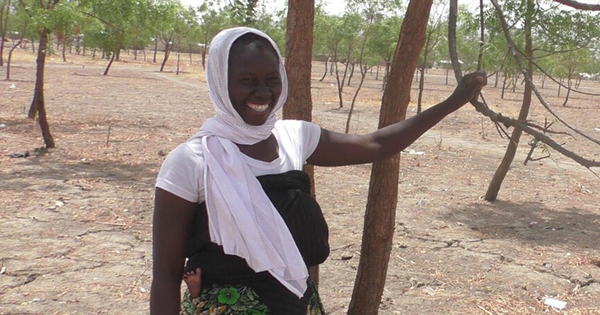 Woman wearing white head scarf next to a tree in Cameroon