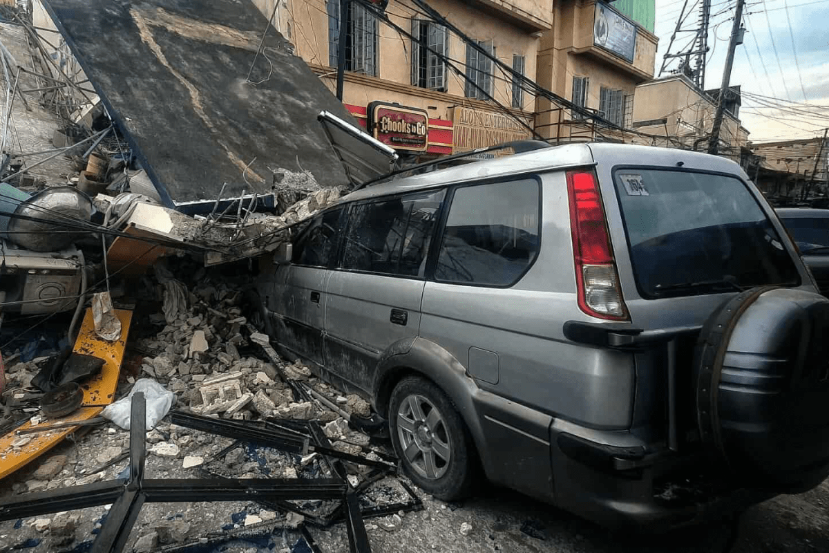 Car crushed under building in Cebu, Philippines, after 2025 earthquake.